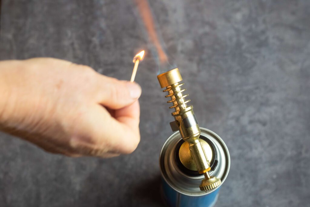 gas cylinder with gas burner burns with flame lit by man with match 1